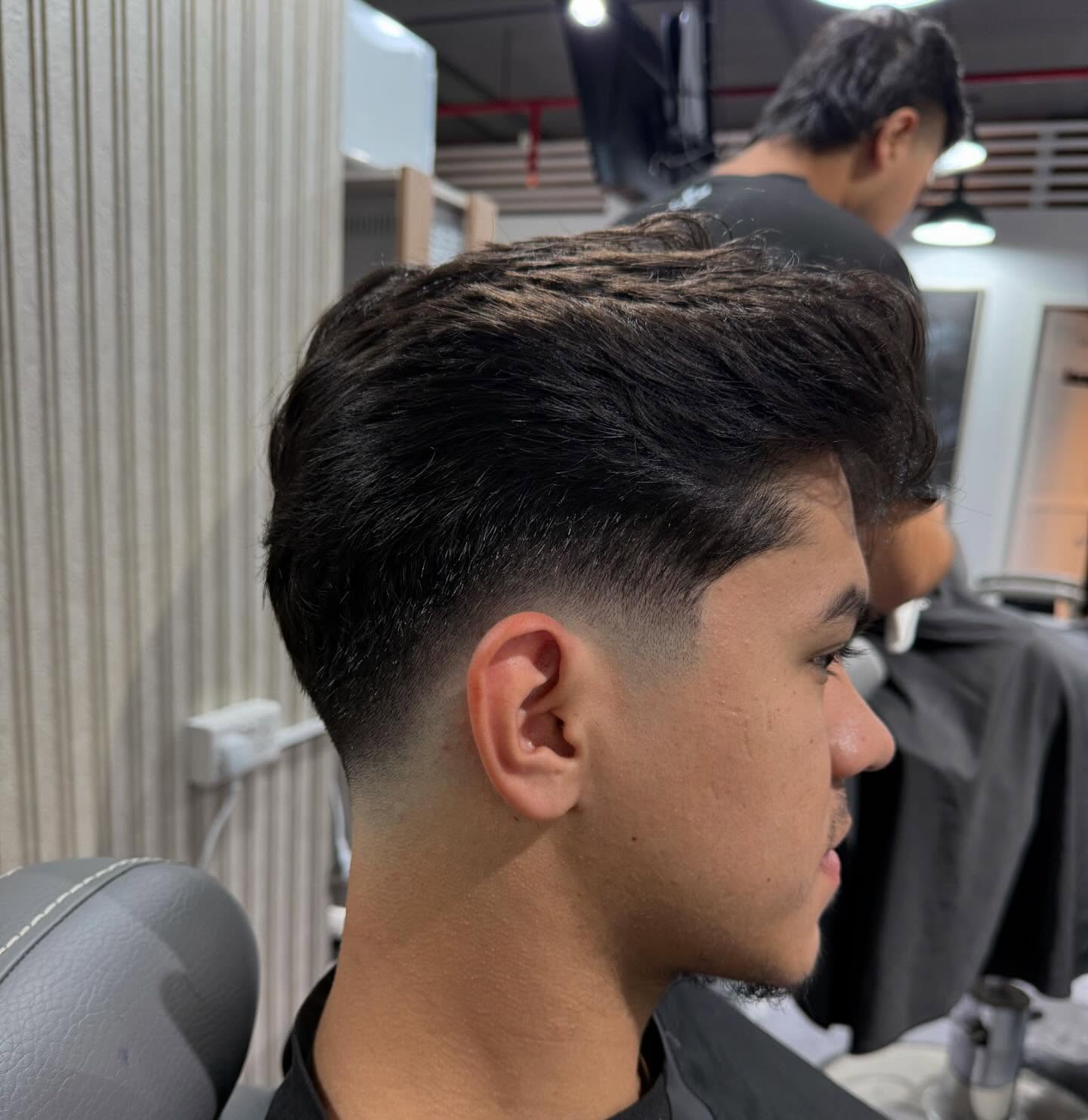 Skin fade — back of head, hard light, close on the blend